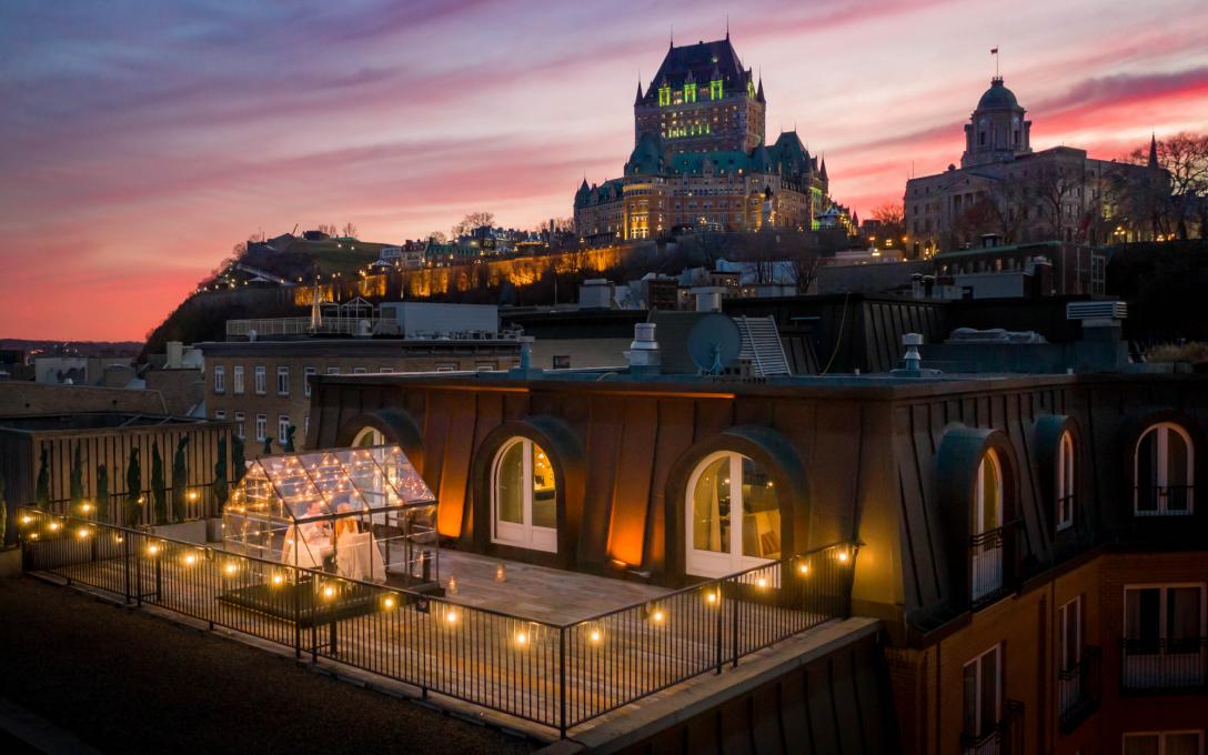 Couple qui mange dans une serre sous les étoiles sur le balcon d'une chambre de l'Auberge Saint-Antoine avec le Château Frontenac en toile de fond