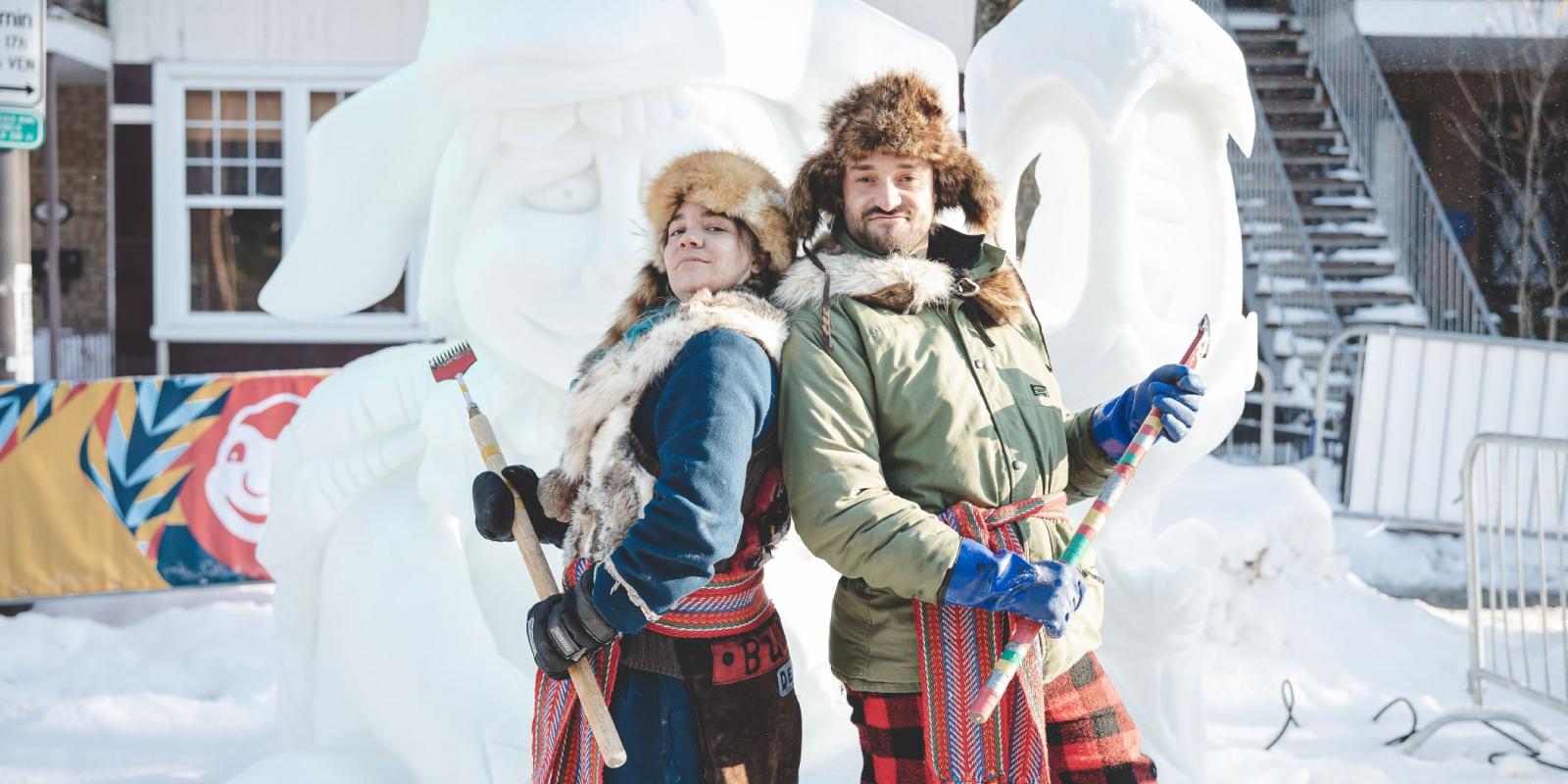 Deux personnages folkloriques devant une sculpture de neige au Carnaval de Québec