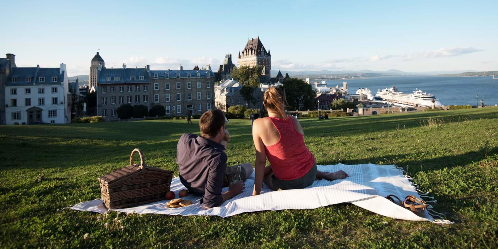 Pique-nique en couple près de la terrasse Pierre-Dugua-De Mons en admirant le Château Frontenac et le fleuve Saint-Laurent. 