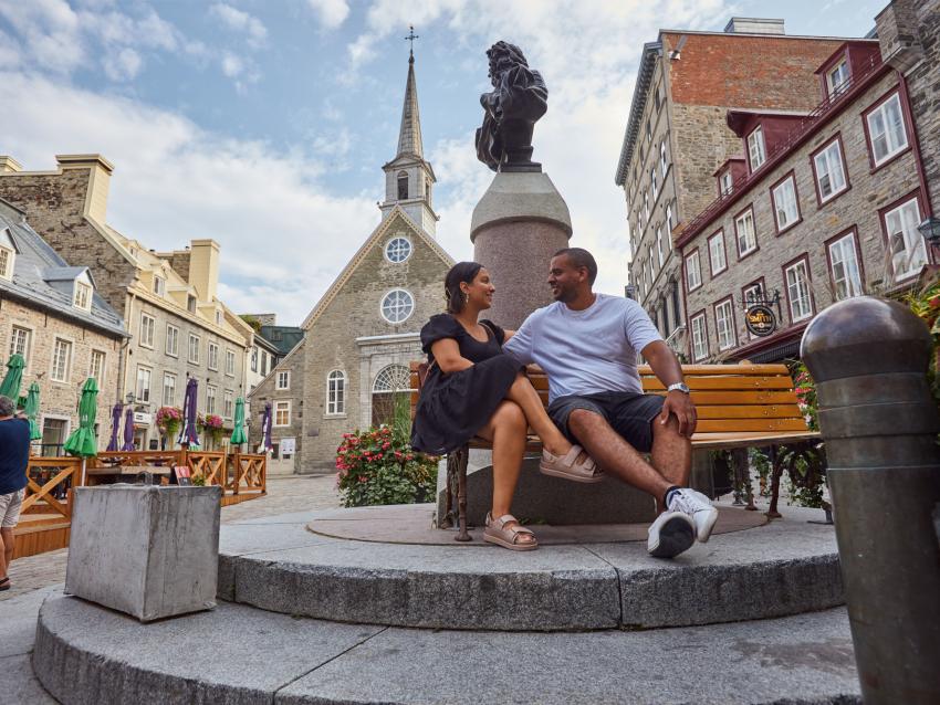 Um casal está sentado em um banco na Place Royale