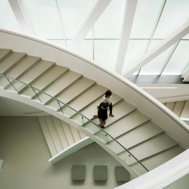 Un couple descend l'escalier intérieur du pavillon Pierre Lassonde au Musée national des beaux-arts du Québec.